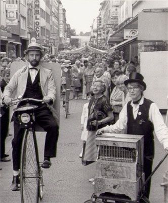 Nostalgiewerbung mit Hochradfahrer und Drehorgelspieler anlässlich einer Geschäftseröffnung